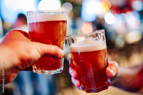 Two friends hands clinking glasses of craft beer at the pub or bar
