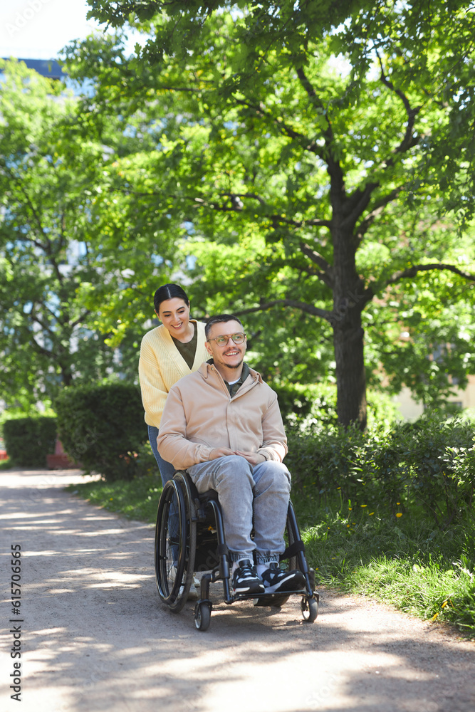 Vertical image of young couple with man with disability walking together in the park in summer Vertical image of young couple with man with disability walking together in the park in summer