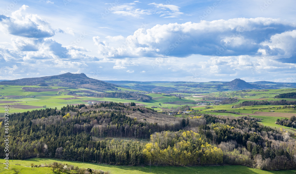 A town with roads, fields, pastures against the backdrop of silhouettes of hills and a cloudy sky