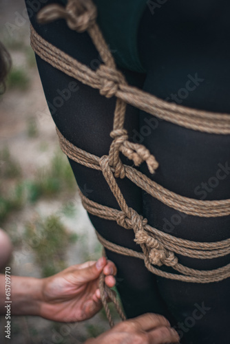 tied up legs of a woman in green body and black tights with a natural rope japanese art of aeshetic shibari bandage kinbaku 