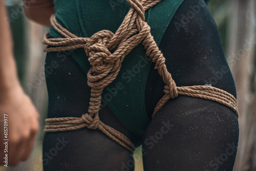 a man ties up a woman in green body and black tights with a natural rope japanese art of aeshetic shibari bandage kinbaku
