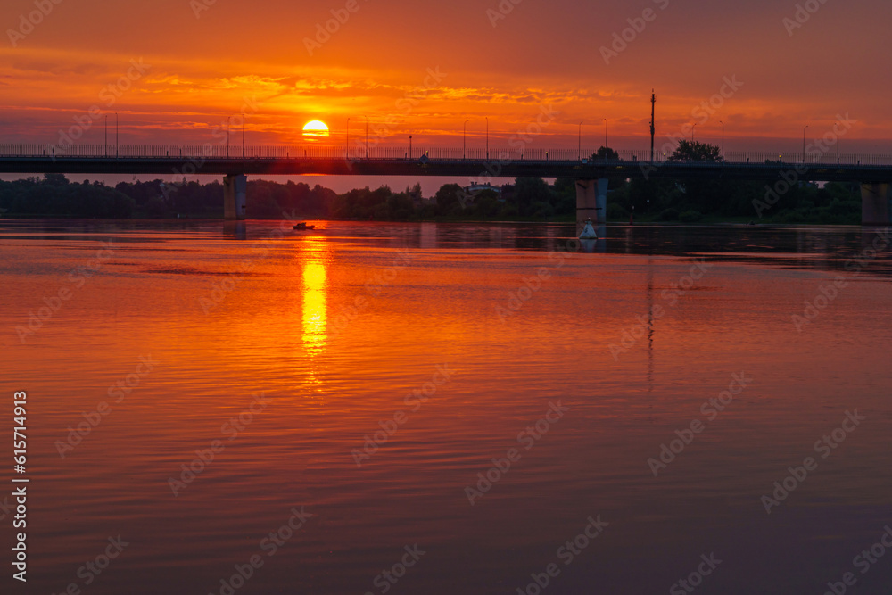 Beautiful summer sunrise over the river. The bridge against the background of the sunrise on a summer morning.