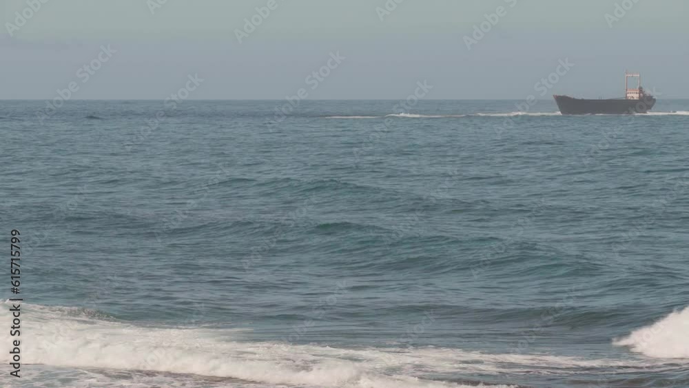 Ocean waves rolling with white foam and blurred ship wrecks on the right on overcast day. Wide shot seascape of Mediterranean sea on Cyprus outdoors Ocean waves rolling with white foam and blurred ship wrecks on the right on overcast day. Wide shot seascape of Mediterranean sea on Cyprus outdoors