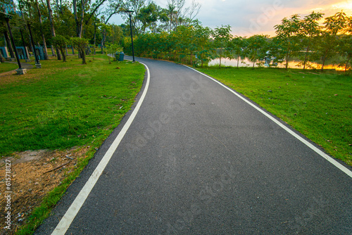 Asphalt walking running and bike road in city park tree forest sunset sky © themorningglory