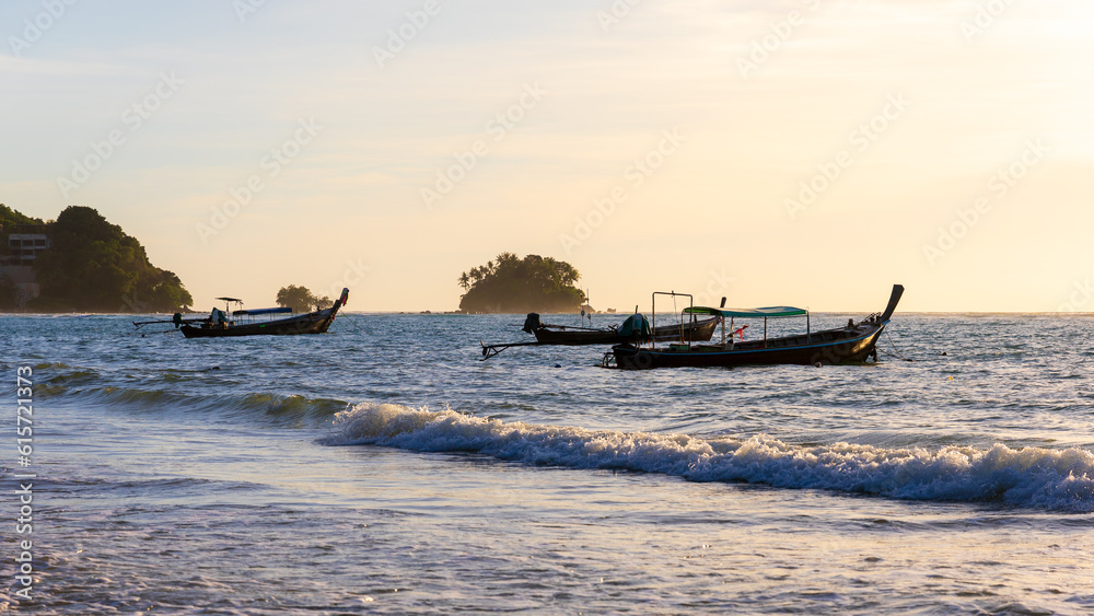 Natural scene of fishing boats anchored on Phuket beach at sunset.