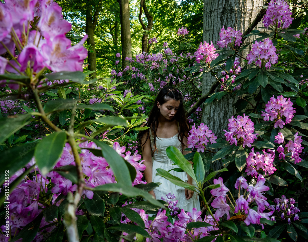 A girl in a white dress stands among the purple flowers in the forest A girl in a white dress stands among the purple flowers in the forest
