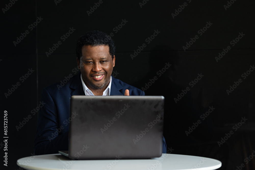 Portrait of handsome black man wearing suit and using laptop computer while sitting Portrait of handsome black man wearing suit and using laptop computer while sitting