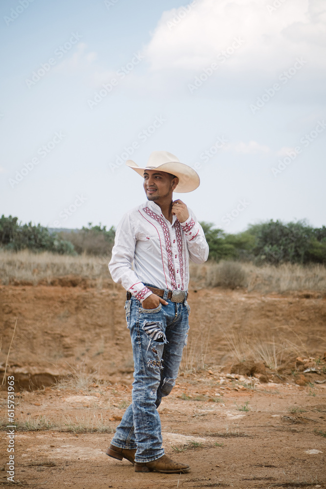 Cowboy wearing jeans and a hat, standing under the sky with fluffy clouds, working on a farm