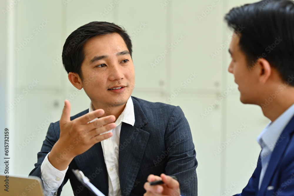 Confident male team leader explaining project details, talking about company strategy and business plan during meeting Confident male team leader explaining project details, talking about company strategy and business plan during meeting