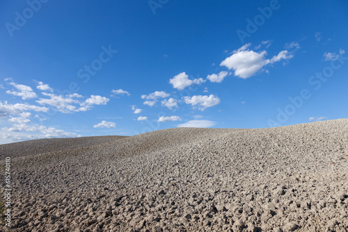 dry plowed hill landscape with sunny blue sky background.