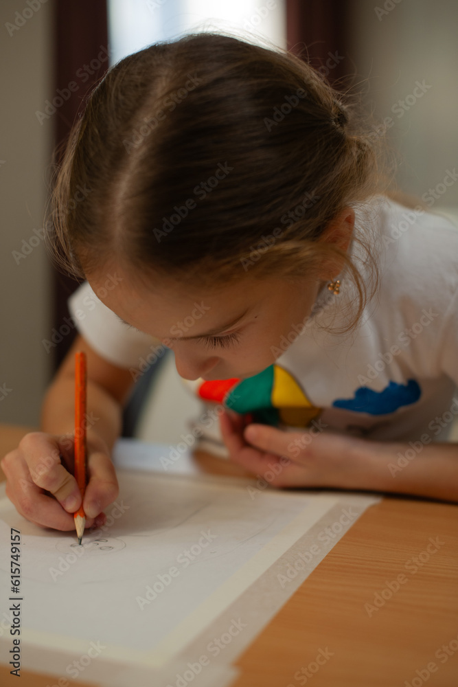 Cute caucasian girl with white t-shirts . Looking down, intently paints a picture with pencil Cute caucasian girl with white t-shirts . Looking down, intently paints a picture with pencil