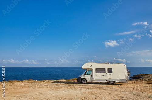 Camper rv caravan on mediterranean coast in Italy. Wild camping on sea shore.