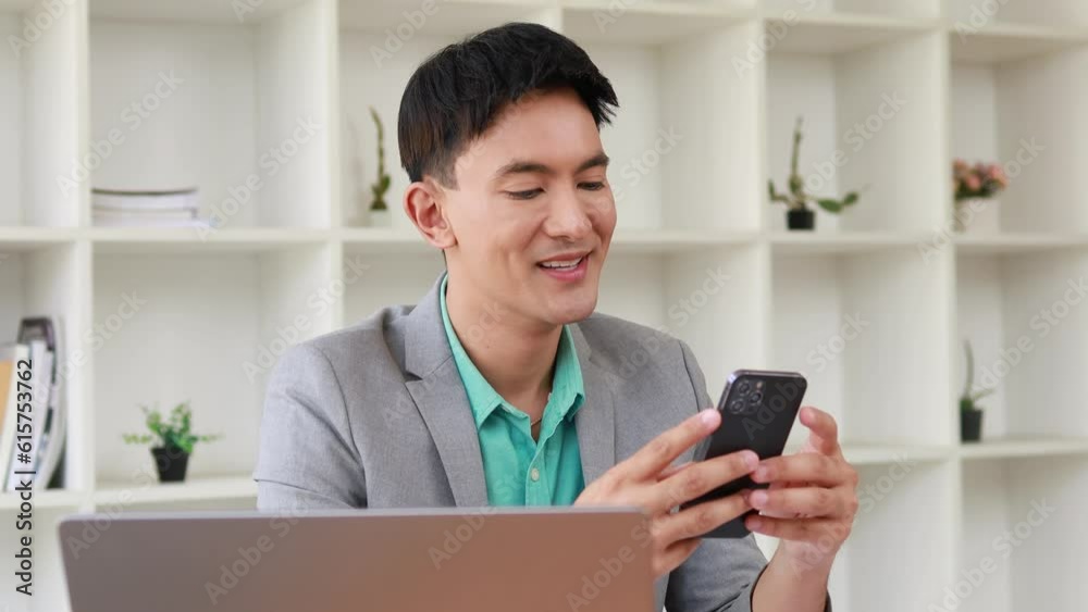 Man working in office, male businessman watching and using his mobile phone to check emails and send messages to chat with colleagues on the internet. The concept of using technology in communication. Man working in office, male businessman watching and using his mobile phone to check emails and send messages to chat with colleagues on the internet. The concept of using technology in communication.
