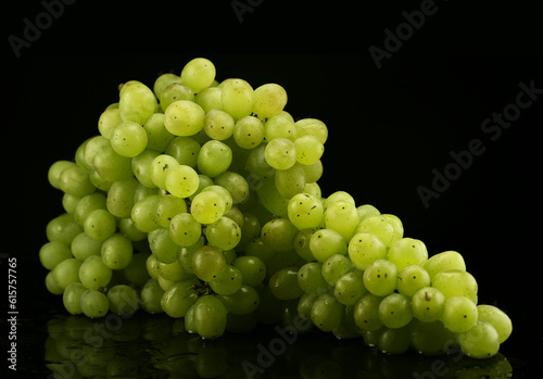 Big brunch of green grapes with drops of water on black background