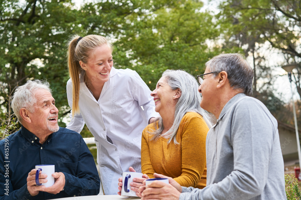 Cheerful nurse and senior people talking in garden of nursing home
