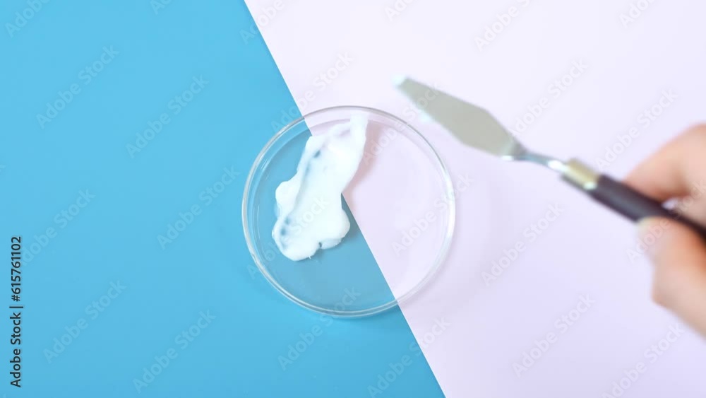Smear of moisturizer moisturizing cream in Petri dishes on pink and blue background close-up. Smear of moisturizer moisturizing cream in Petri dishes on pink and blue background close-up.