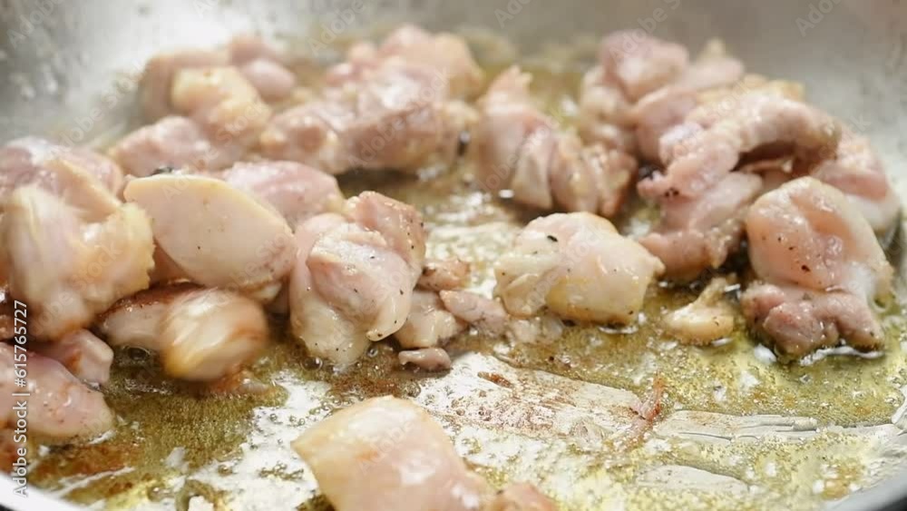 Cooking and stirring chicken pieces in a frying pan.
Cooking and stirring chicken pieces in a frying pan.