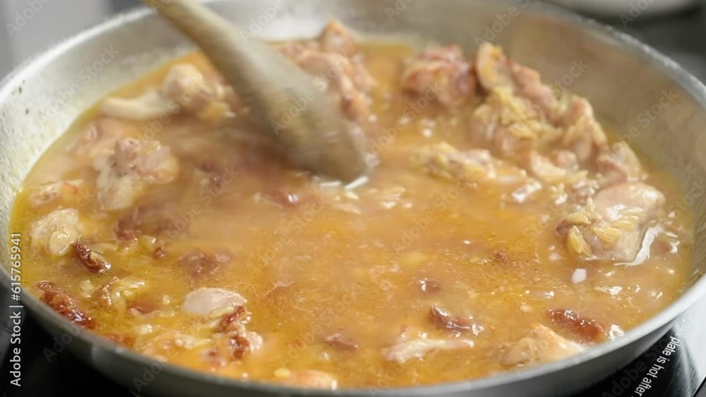 Cooking and stirring chicken with orzo pasta in a frying pan.
Cooking and stirring chicken with orzo pasta in a frying pan.