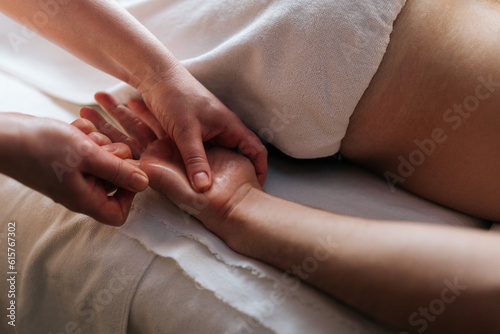 Bilde på lerret Close-up cropped shot of unrecognizable professional masseuse hands doing finger and palm massage to male client lying on massage table in spa salon