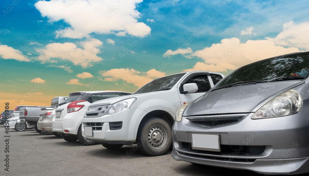 Cars parking in a row in stock background. Vehicle transportation trip inventory merchandise. Car parked in large asphalt parking lot with white cloud and blue sky background. Outdoor parking lot