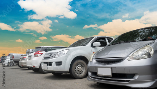 Cars parking in a row in stock background. Vehicle transportation trip inventory merchandise. Car parked in large asphalt parking lot with white cloud and blue sky background. Outdoor parking lot © merrymuuu