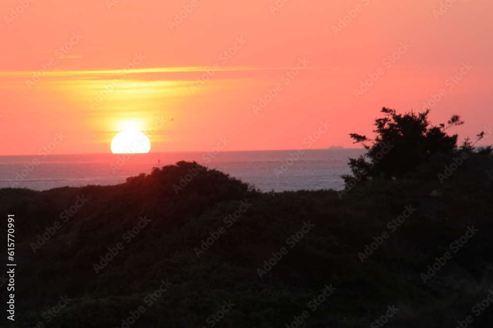 at the sea the red-golden sun shines out from behind the clouds before it sets at the sea the red-golden sun shines out from behind the clouds before it sets
