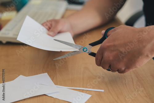 фотографія Left-handed man's hand cutting paper with scissors wave