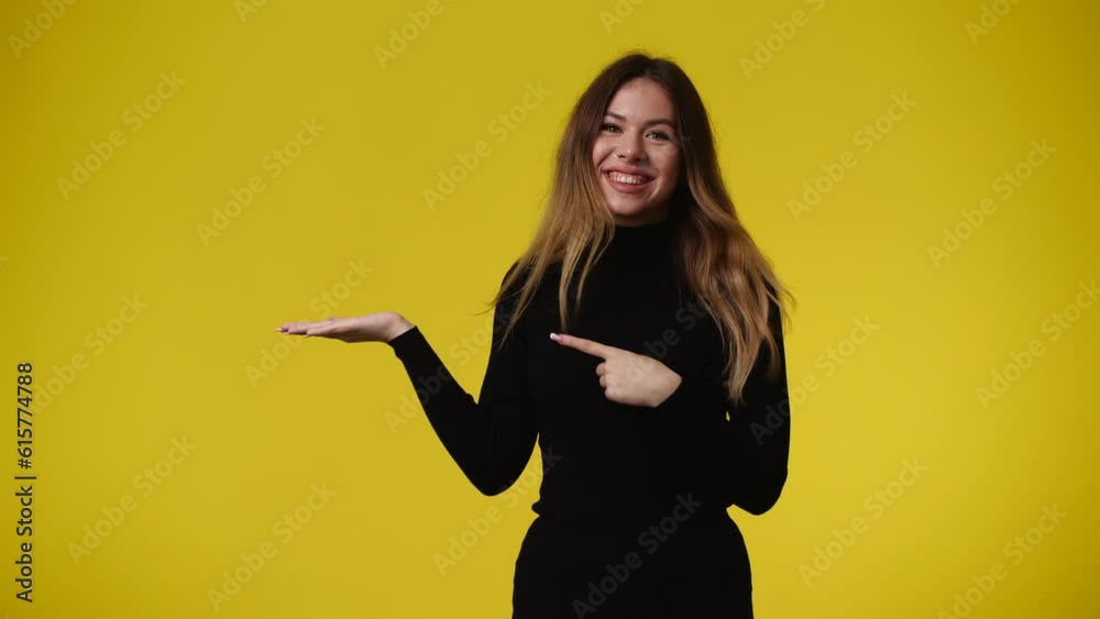 4k video of one girl who shows something in his right hand over yellow background.