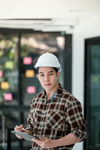 Portrait Asian man engineer holding tablet in the office.  © Treerat