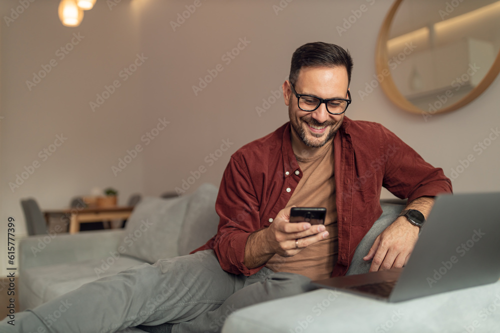 Happy man got message from on of his friends, being at home, working online.