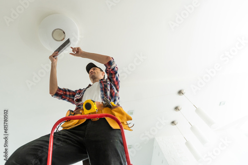 electrician installing led light bulbs in ceiling lamp