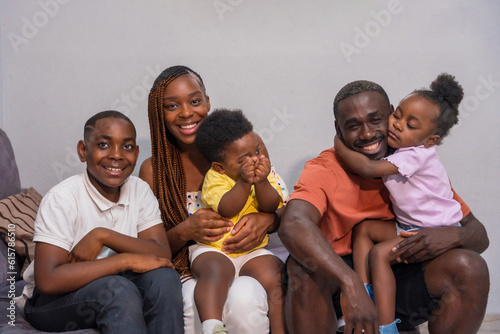 Portrait of black African ethnicity family with children on the sofa at home having fun