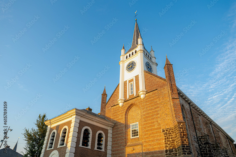 Obraz premium White clock tower of Reformed Church (Dutch: Gereformeerde or Hervormde kerk) The oldest building in the town centre, Bouwstraat, Ommen, A city in the Dutch province of Overijssel, Netherlands.