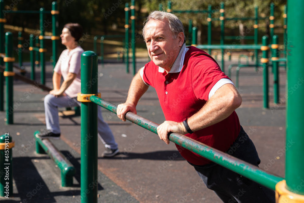 Fototapeta premium Elderly man is doing push-ups from the crossbar