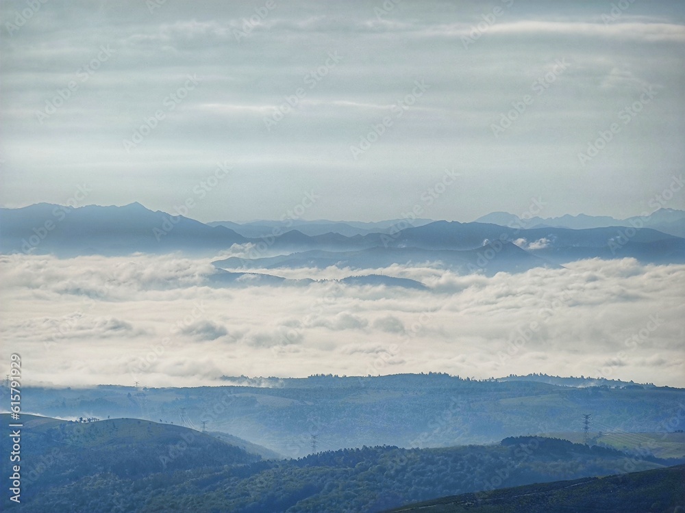 View of valley with clouds and fog and mountains in the background