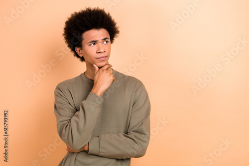 Photo of serious pensive man hand touch chin look interested empty space contemplate hesitate isolated on beige color background © deagreez