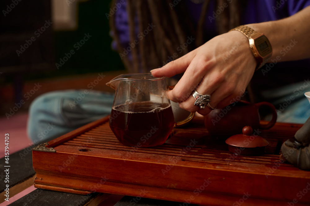 person pouring tea in a pot, in the style of influenced by ancient chinese art, low key