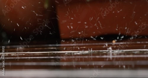 Summer rain water drops falling on balcony leaving ripples on wooden line textured ground