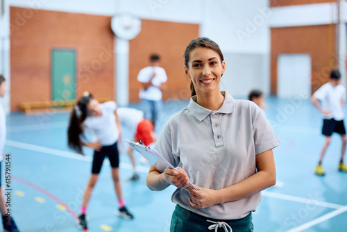 Happy sports teacher during physical education class at school gym looking at camera.