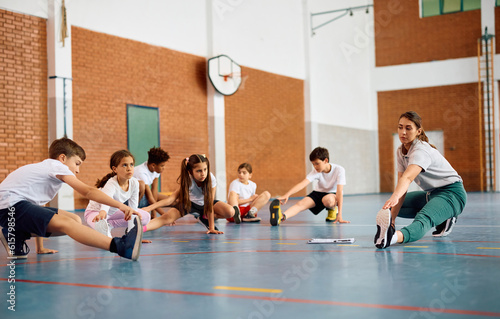 Group of school kids exercising with their sports teacher during physical education class.