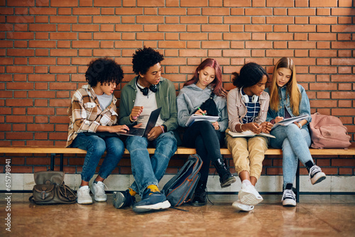 Multiracial group of teenagers studying together in high school hallway. photo