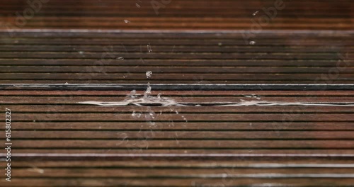 Summer rain water drops falling on wood slow motion close up