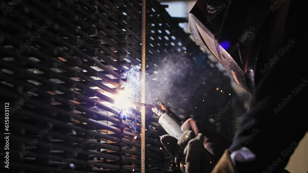 Welder wearing a helmet works at a construction site. Sparks from electricity. Welder wearing a helmet works at a construction site. Sparks from electricity.