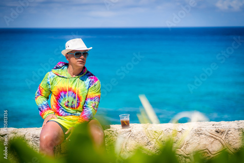 A caucasian man enjoying a summer sunny day on a boat at Isla Mujeres Cancun. Colorful clothing. happy young man smiling and waving.
