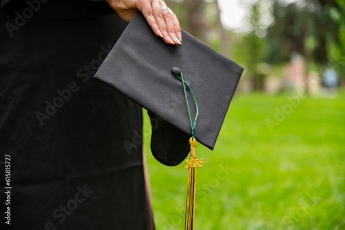 Graduate Wearing Gown and holding Motarboard In Park photo