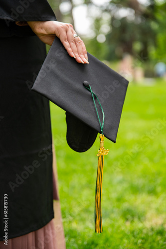 Graduate Wearing Gown and holding Motarboard In Park photo