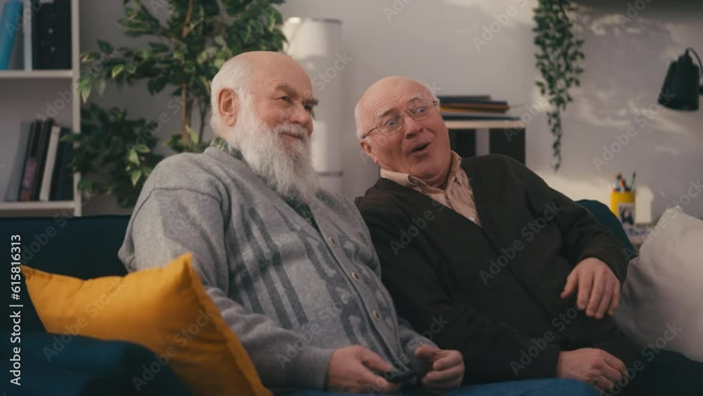 Surprised senior men watching shocking news on TV at home, resting on sofa Surprised senior men watching shocking news on TV at home, resting on sofa