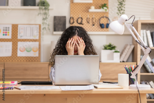 Asian woman sitting at desk in front of laptop stressed out face and headache shows her stressful  with work from home office. Female thinking about work mistake or workload has depression.