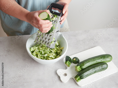 Foto woman hands grating zucchini in a bowl using a stainless steel hand grater