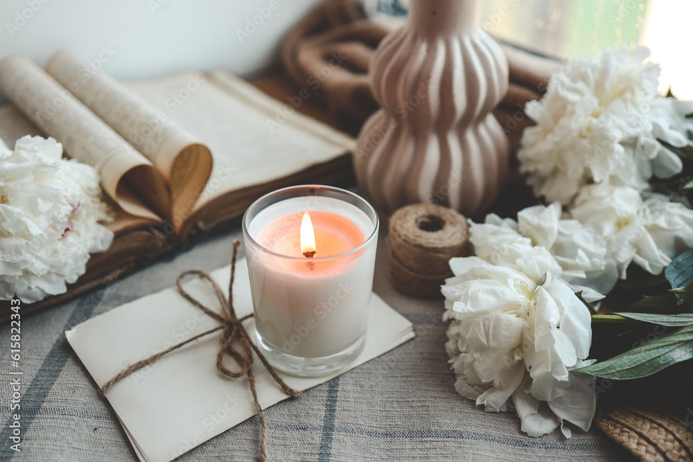 Burning candle and white peonies, vintage aesthetic